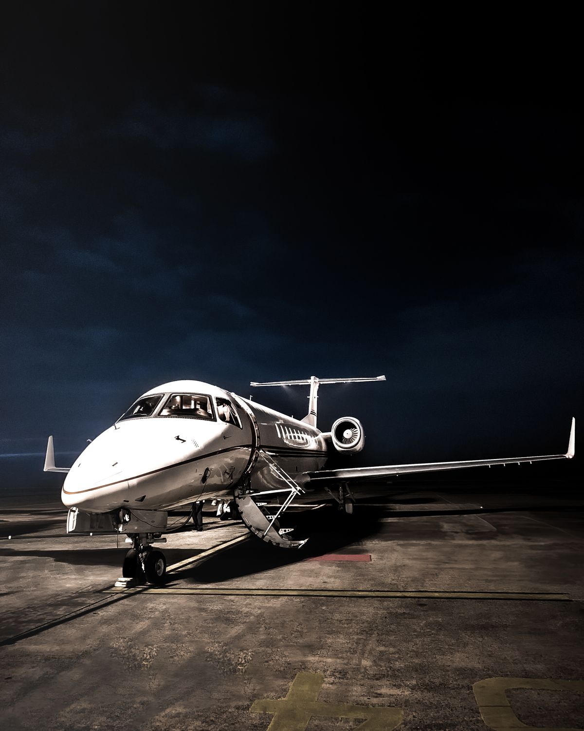 Aeronave privada iluminada em pista, à noite.