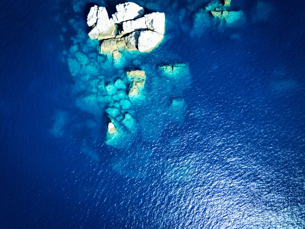 Água azul-turquesa sobre formações rochosas submersas.