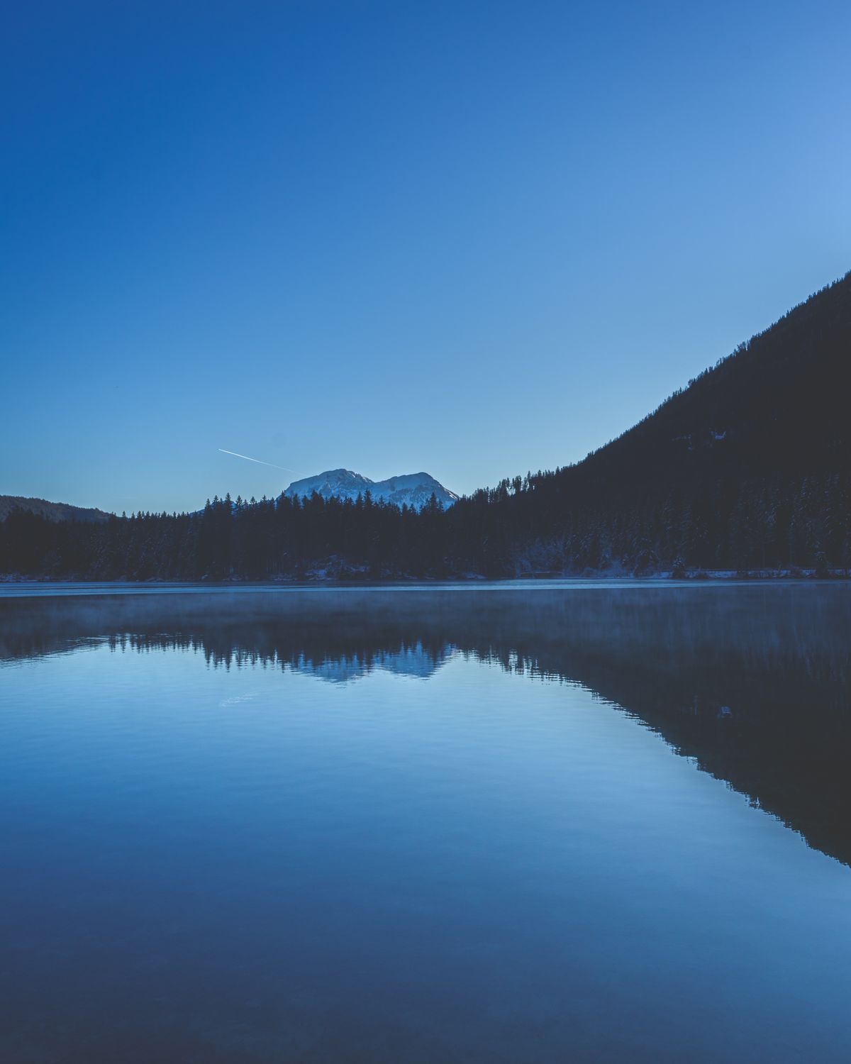 Lago imóvel ao crepúsculo, com a montanha reflectida na água.